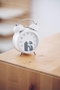 white alarm clock sitting on wooden night stand